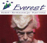 a man wearing glasses and a wig is standing in front of an everest hotel logo .
