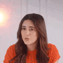 a woman wearing a red sweater is looking at the camera