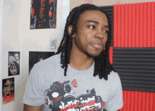 a man with dreadlocks wears a gray shirt that says n.r.o.m.p.