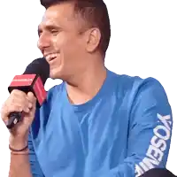 a man in a blue shirt is holding a microphone with a yosemite logo on his arm