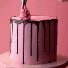 a pink cake with chocolate dripping from it and the words mrcakes on the bottom