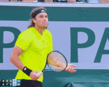 a man in a neon yellow shirt is holding a tennis racquet in front of a papa sign