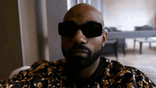 a bald man with a beard wearing sunglasses and a floral jacket