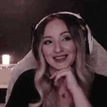 a woman wearing headphones and a necklace is smiling while sitting in a chair .