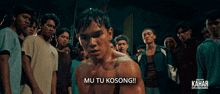 a group of men are standing around a shirtless man with the words mu tu kosong written below him