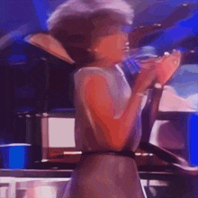 a woman singing into a microphone in a dark room