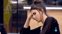 a woman is sitting at a table with her hand on her head while watching a tv show called la habitacion