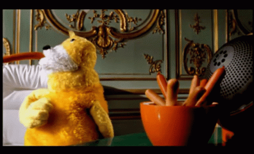 a yellow stuffed animal is standing next to a bowl of sausages
