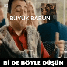a man sitting at a table with a picture of a man hugging another man and the words büyük babun bi de böyle düşünün