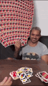 a man in a batman shirt is playing uno