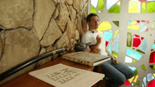 a man sits in front of a stained glass window with a book titled l' encyclopedia