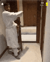 a man in a bathrobe is standing in a hallway next to a door that says fm