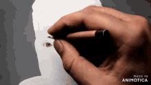 a hand is drawing a face with a pencil and the words made in animotica are below it