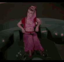 a woman in a pink dress is sitting on a telephone and giving a thumbs up .