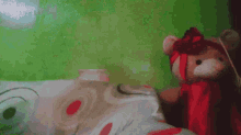 a teddy bear with a red ribbon around its neck is on a bed
