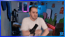 a man in a white shirt stands in front of a microphone in front of a mario wall
