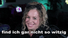 a woman is smiling in front of a microphone with the words find ich gar nicht so witzig in the corner