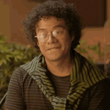 a man with curly hair wearing glasses and a scarf around his neck