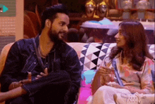 a man and a woman are sitting next to each other on a couch and talking to each other .