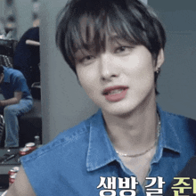 a young man wearing a blue shirt and a necklace with korean writing