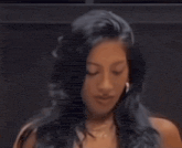 a woman with long dark hair and hoop earrings smiles
