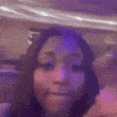 a close up of a woman 's face with purple lights in the background