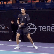 a man is playing tennis in front of a banner that says tere on it