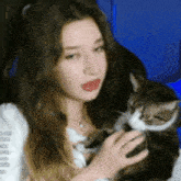 a woman is holding a cat in her lap .