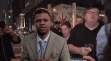 a man in a suit and tie is standing in front of a crowd of people