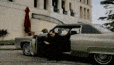 a man in a black suit is getting out of a green car