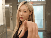 a woman pointing at the camera in front of a red exit sign