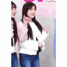 a girl in a white jacket and blue jeans is standing next to two other girls