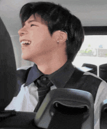 a man in a black shirt and tie is smiling