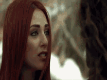 a woman with red hair is looking at another woman .