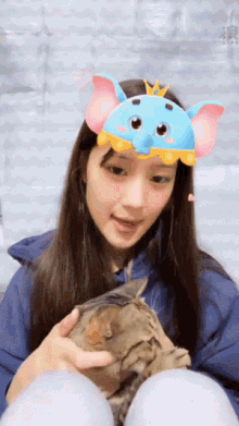 a girl wearing a blue elephant headband holds a small animal