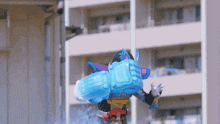 a cartoon character with a huge blue item on his back is standing in front of a building