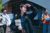 a woman in a green jacket is holding a book with the number 8 on it