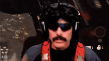 a man with a mustache and sunglasses is wearing headphones and waving his hand in a video game .