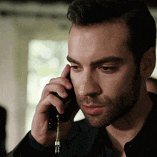 a man with a beard is talking on a cellphone
