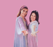 two girls are standing next to each other with their hands outstretched