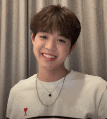a young man wearing a white shirt with a red heart on the chest
