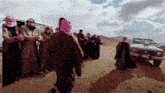 a group of people standing on a dirt road with the letters cauns on the bottom left