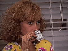 a woman is drinking from a small white cup