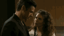 a man and a woman are looking at each other in front of a picture