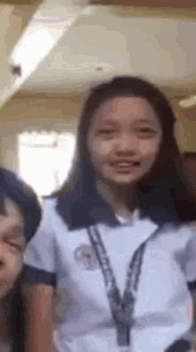 a girl in a school uniform is standing next to a boy in a room and smiling .