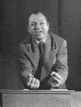 a man in a suit and tie is standing at a podium giving a speech