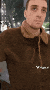 a man wearing a brown jacket with a viggle.ai logo on the front