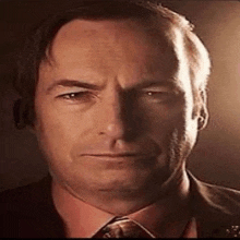 a close up of a man in a suit and tie making a serious face .