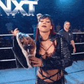 a woman in a leather jacket is holding a wrestling championship belt