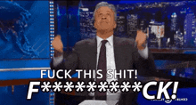 a man in a suit and tie is sitting on a stage and says fuck this shit .